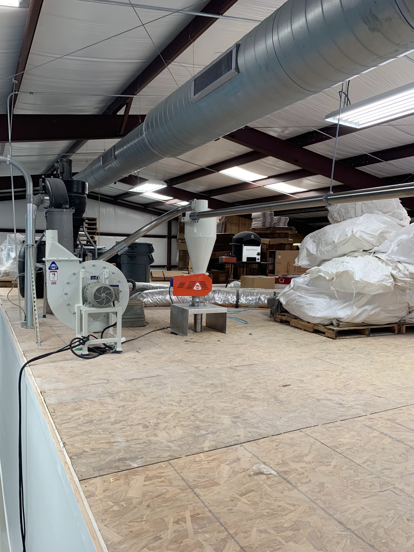 Conveying blower and cyclone receiver on a rotary airlock above bulk bags on pallets on a mezzanine