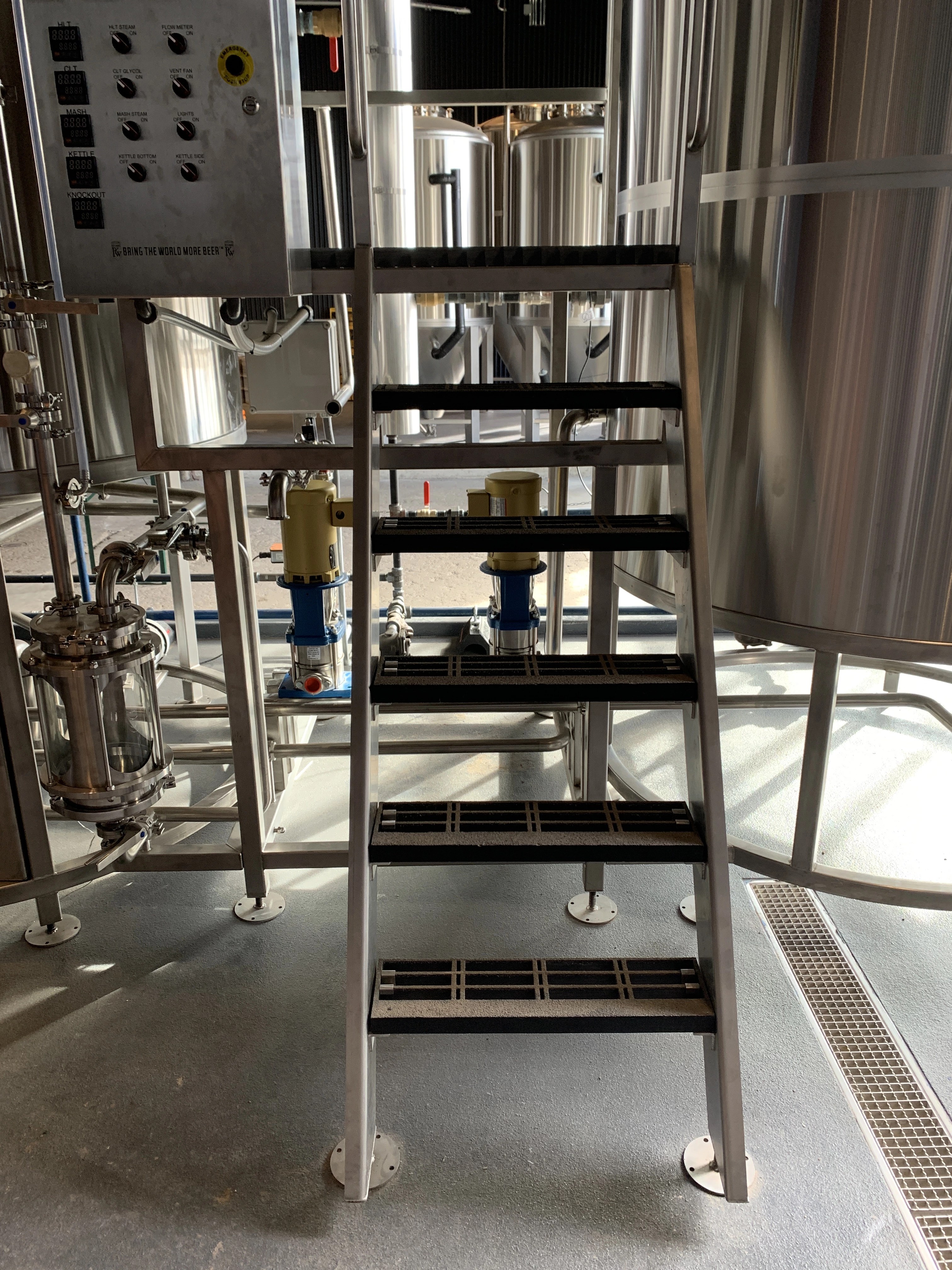 Brewhouse platform with a control panel, stairs and stainless tanks at Central Machine Works