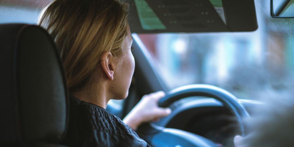 a woman sitting in a car with a steering wheel