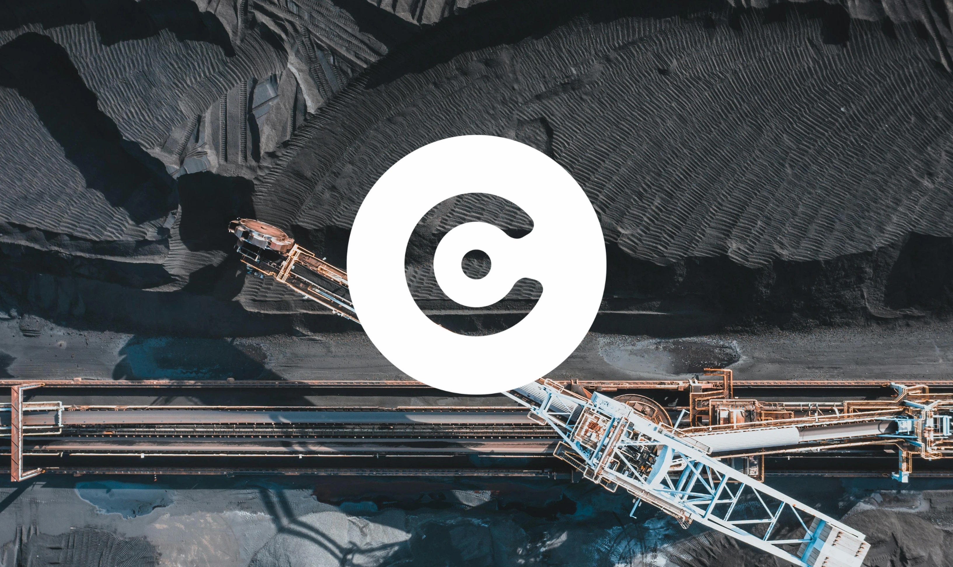 The image shows an aerial view of an industrial mining conveyor system over piles of black coal or similar dark material, forming textured patterns. Superimposed centrally is a large white circular logo in the middle.