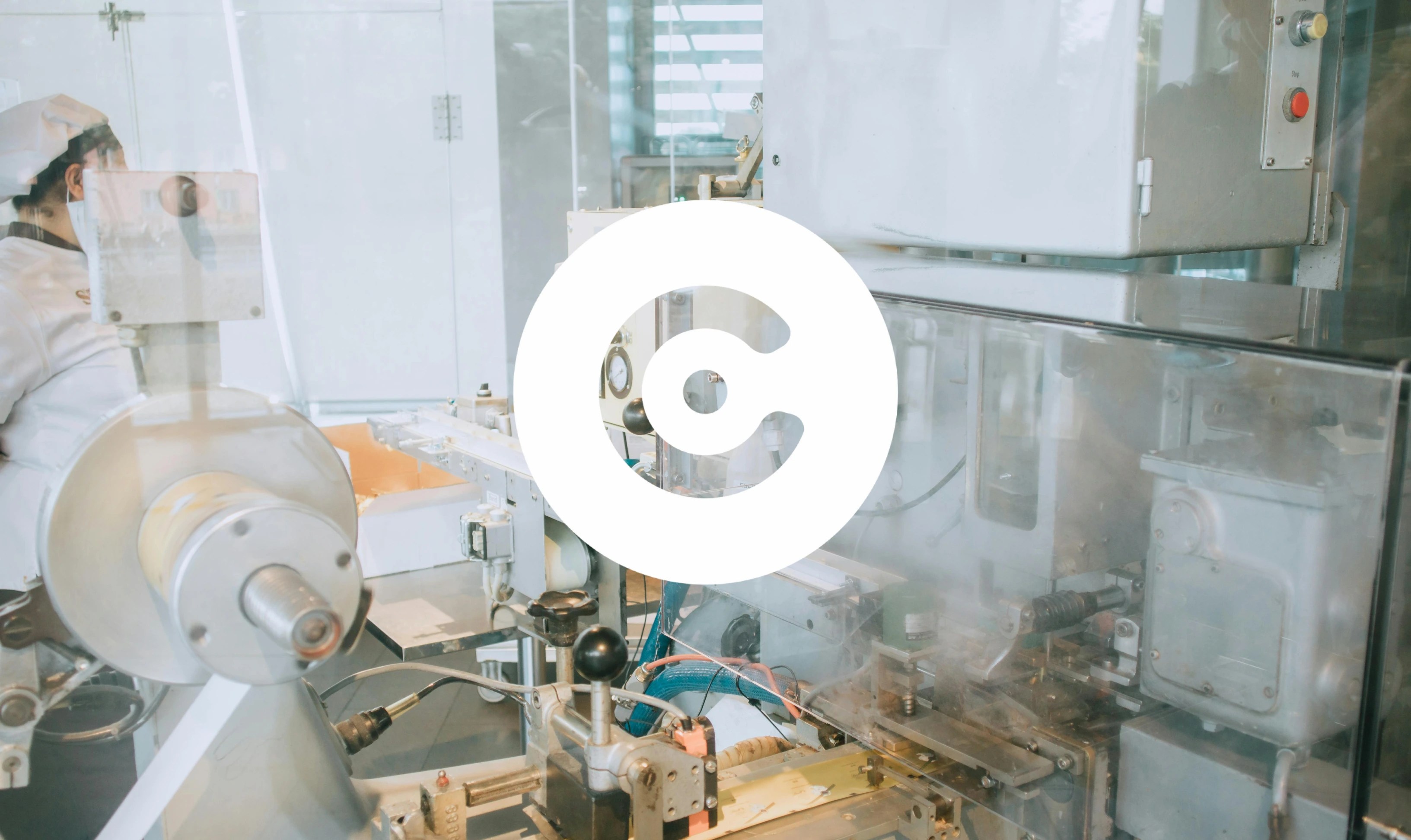 Industrial machinery in a factory setting with a worker in protective clothing, overlaid with a large circular logo in the center.