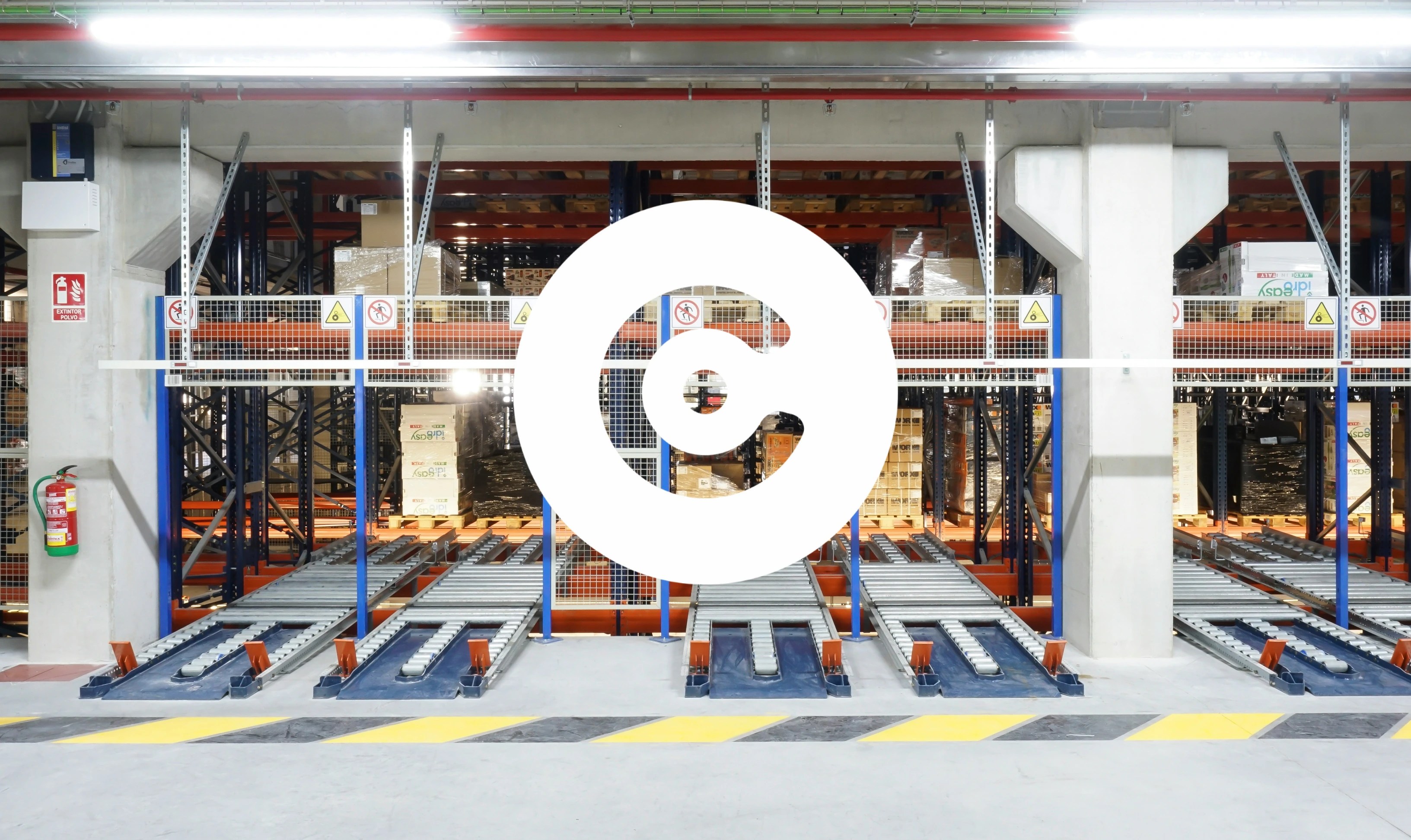 Automated warehouse interior with pallet flow racks, conveyor lanes, and stacked goods organized for storage and distribution.