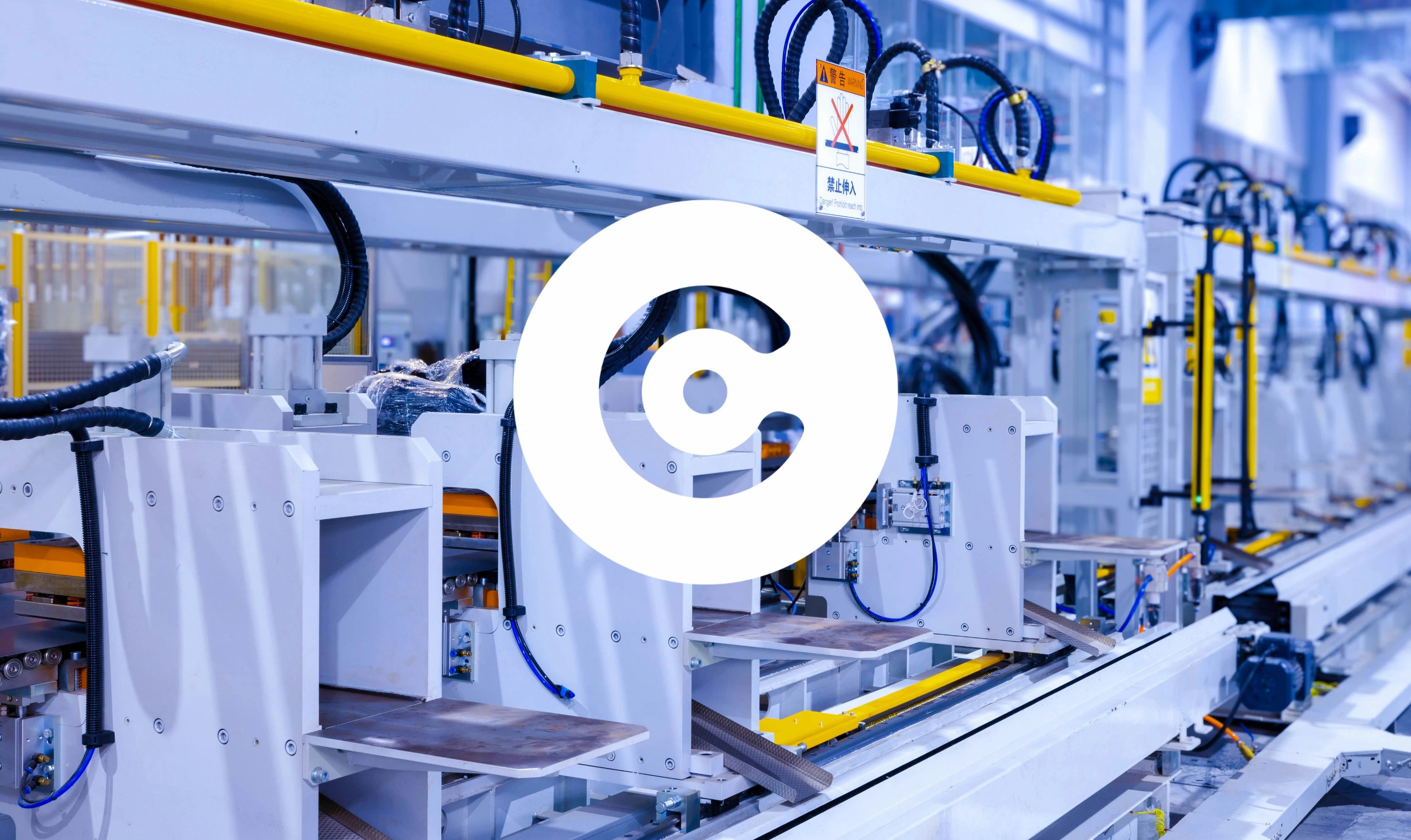 Automated industrial production line with robotic machinery, conveyor systems, and safety signage inside a modern factory.