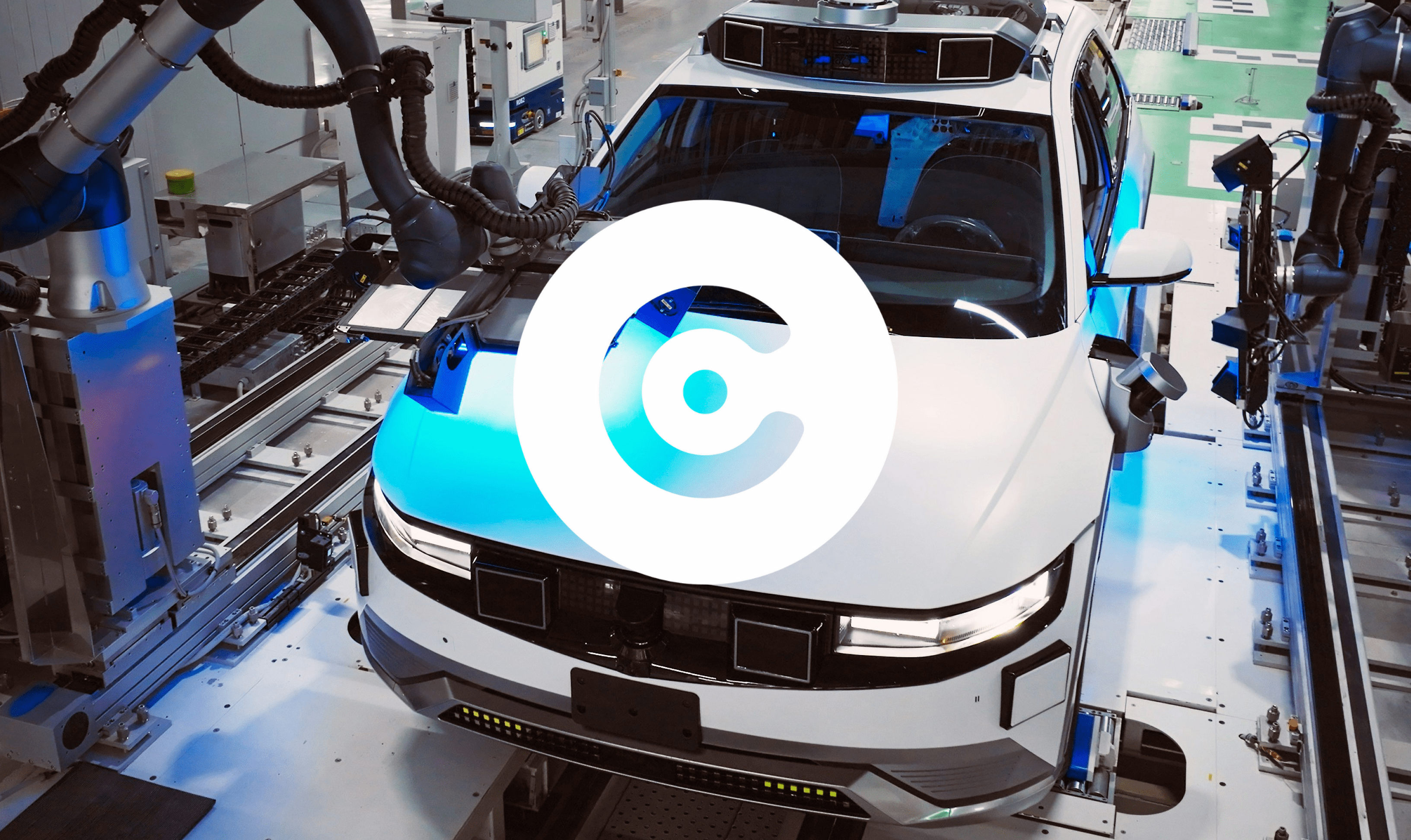 Autonomous vehicle on an assembly line surrounded by robotic arms in a high-tech factory.