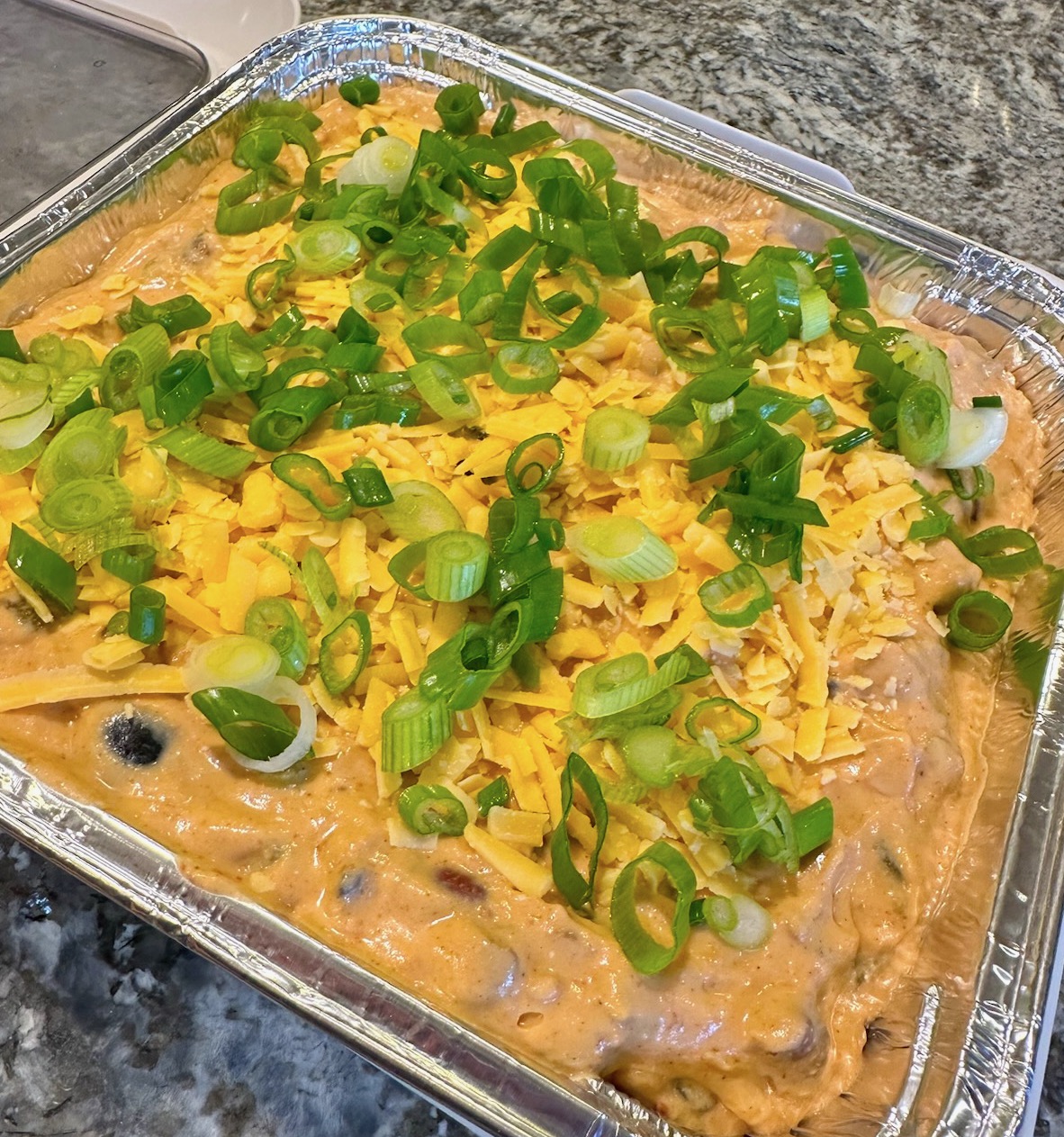 This bean dip recipe with cream cheese, refried beans and chorizo will be a party favorite. It's topped with green onions and shredded cheddar cheese.