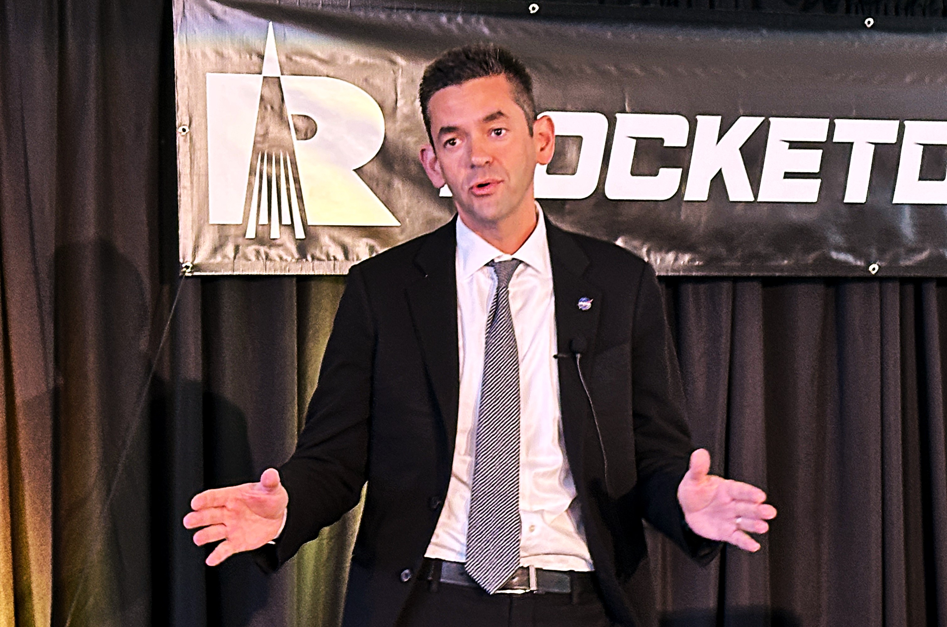 Jared Isaacman on stage with Rocketdyne logo in background