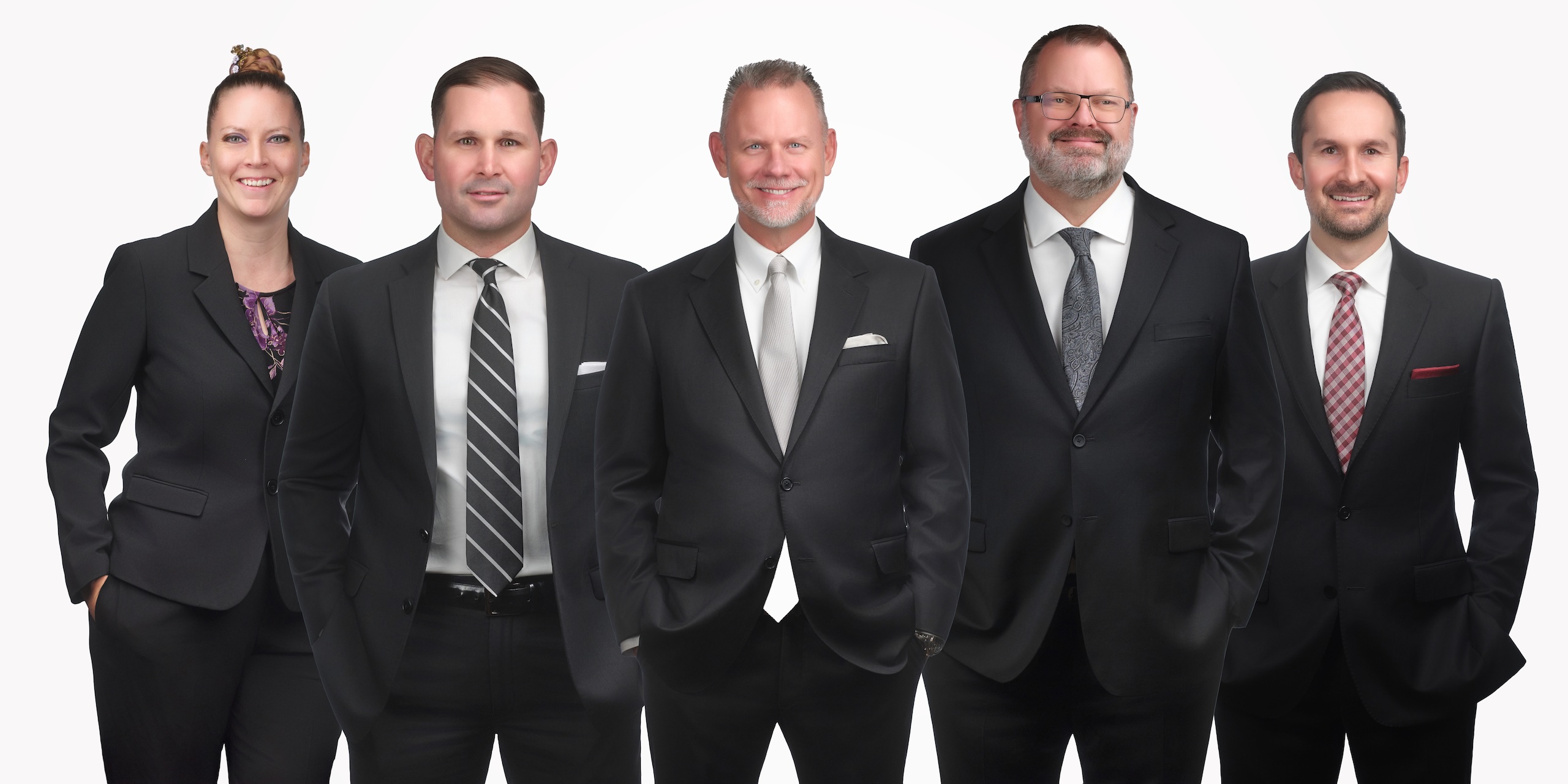 A group of five professionals in business attire, smiling confidently against a white background.