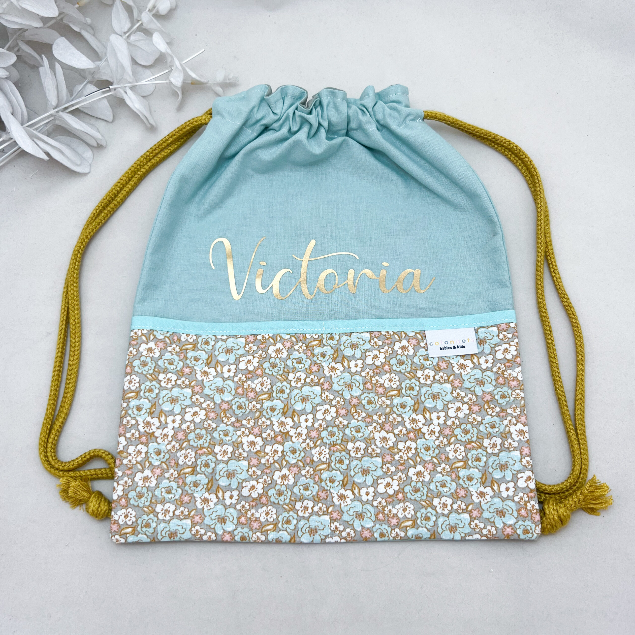 Mochila personalizada cuerdas flores nombre dorado. Varios colores