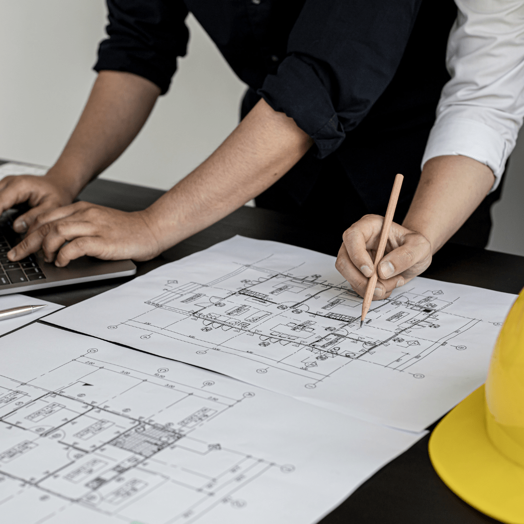 close-up of blueprints on desk and two people looking over them.