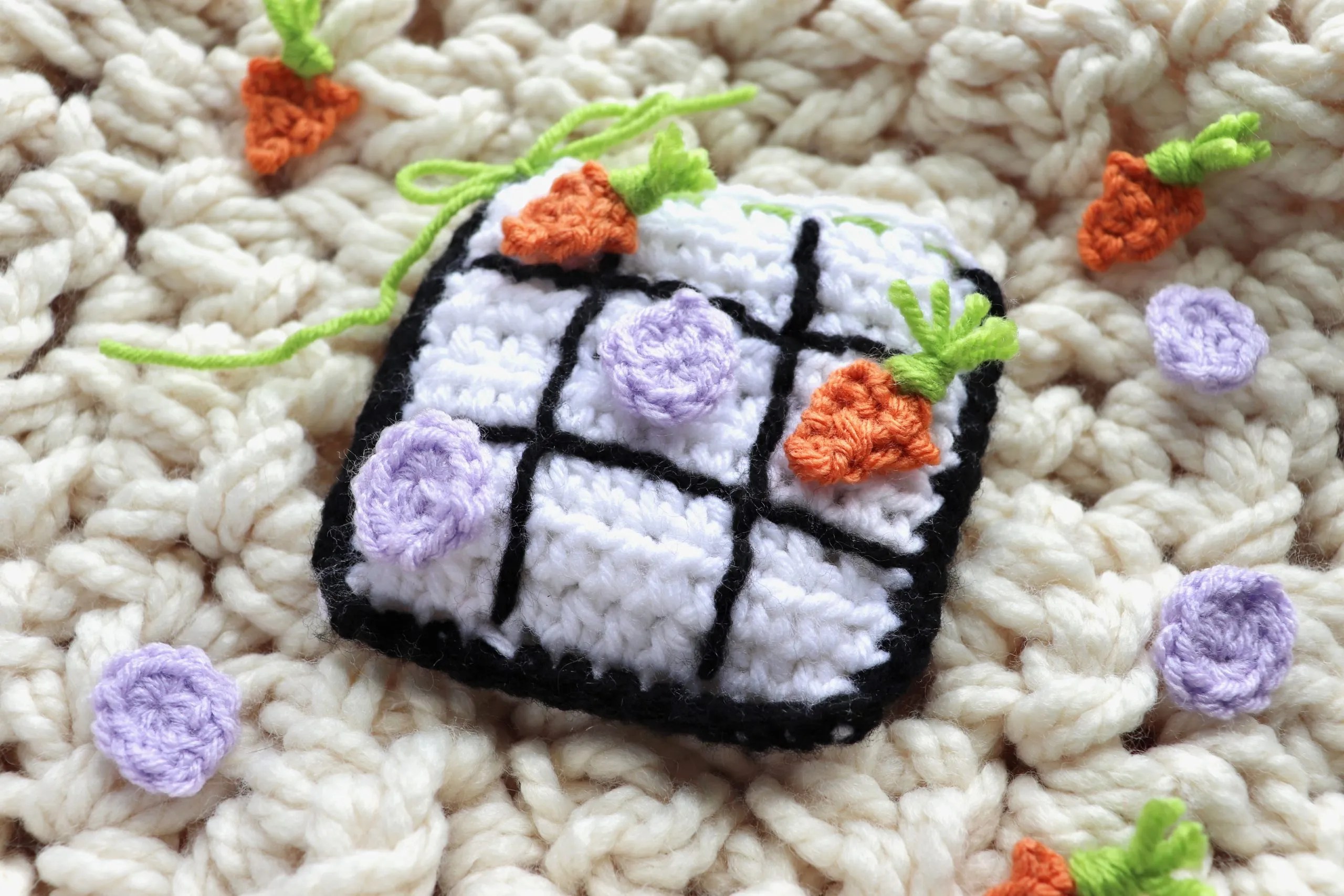 Crochet Tic tac toe board for easter. Orange carrots and purple easter eggs are used for the game pieces