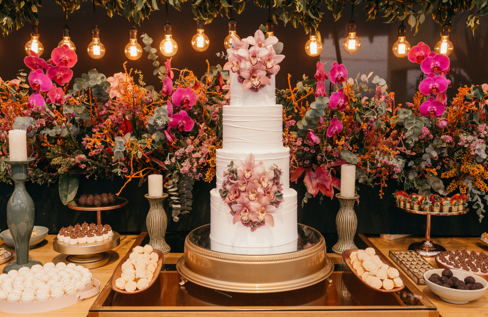 three-tiered wedding cake with botanical decorations surrounded by fresh flowers