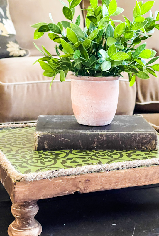 A diy wood riser using rope, wood candlestick holders, antique wax and green and brown peel and stick tiles.