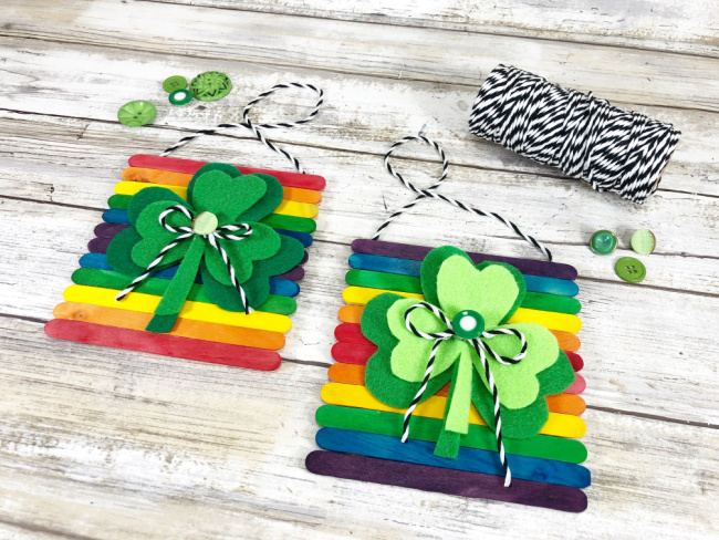 attaching baker's twine to wooden stick rainbow and shamrock signs as hangers