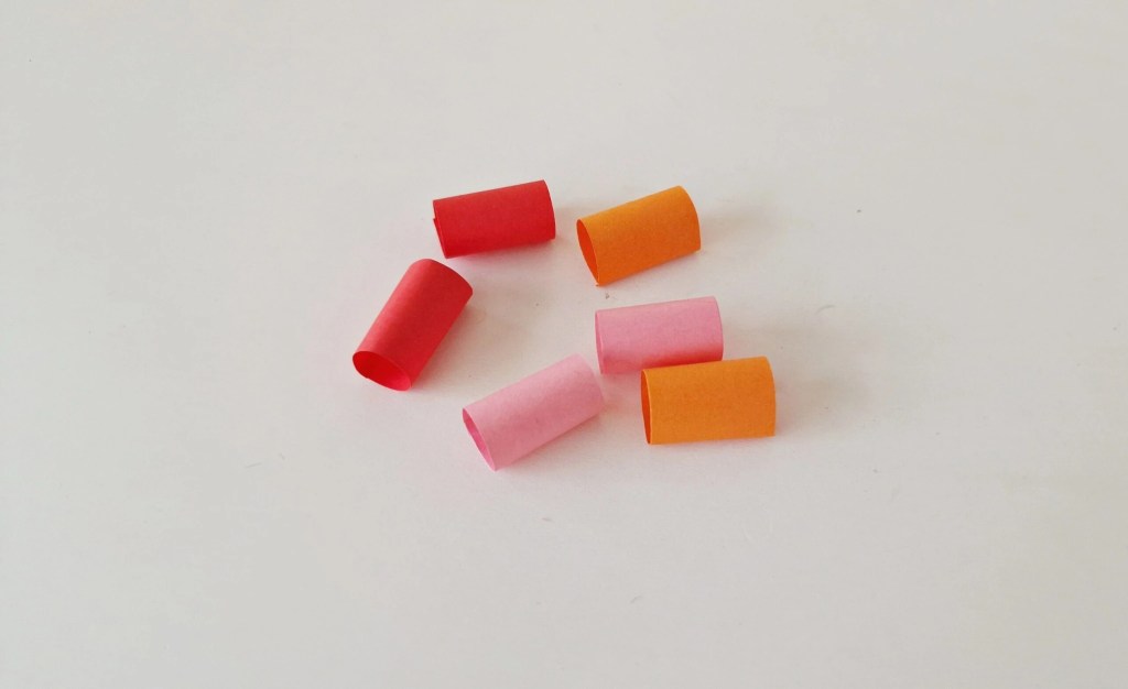 Six rolled paper loops in red, pink, and orange for the caterpillar body.