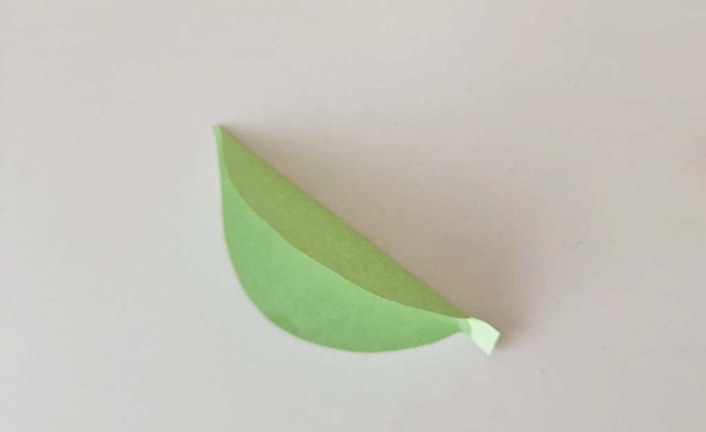 Green paper leaf folded in half for the moving caterpillar craft.