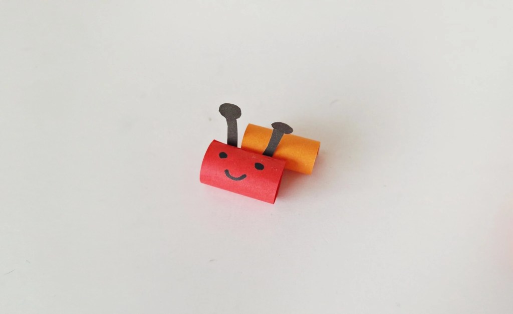Paper caterpillar head with a smiling face and antennae.