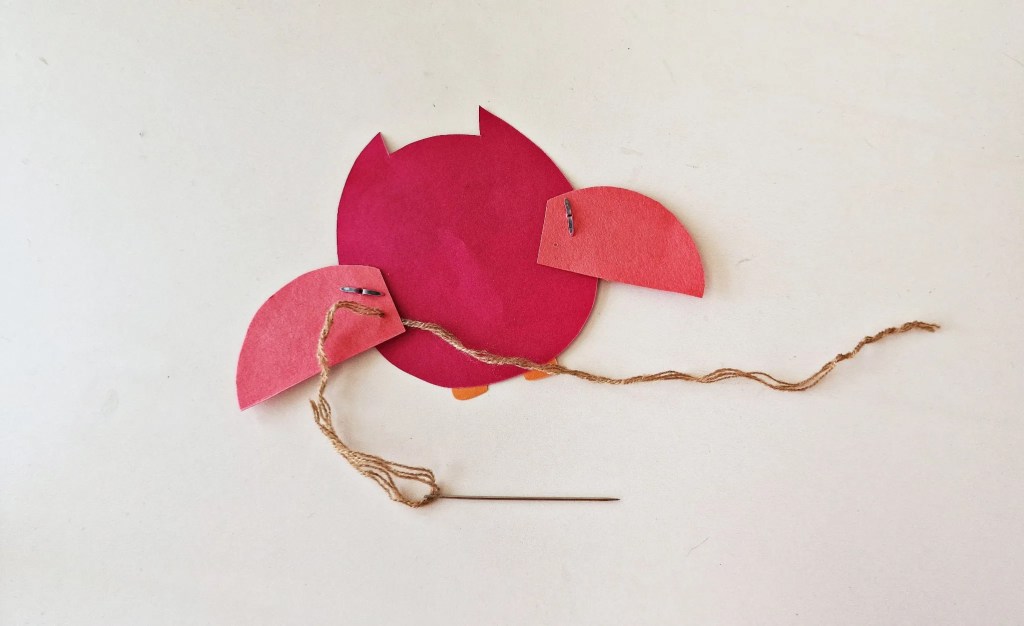 Threading string through the owl’s wings to create the flapping mechanism for a moving owl craft.