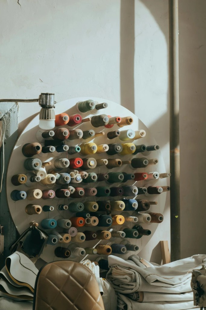 Circular wall-mounted thread organizer filled with assorted sewing thread spools.