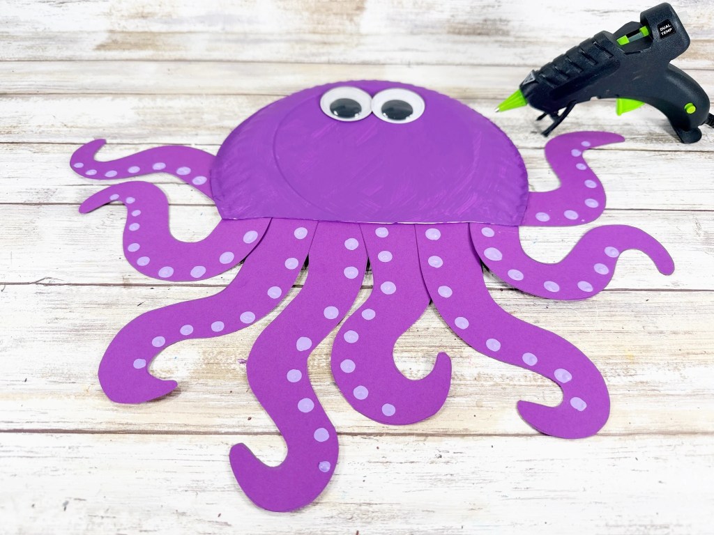 Attaching large googly eyes to the paper plate octopus.