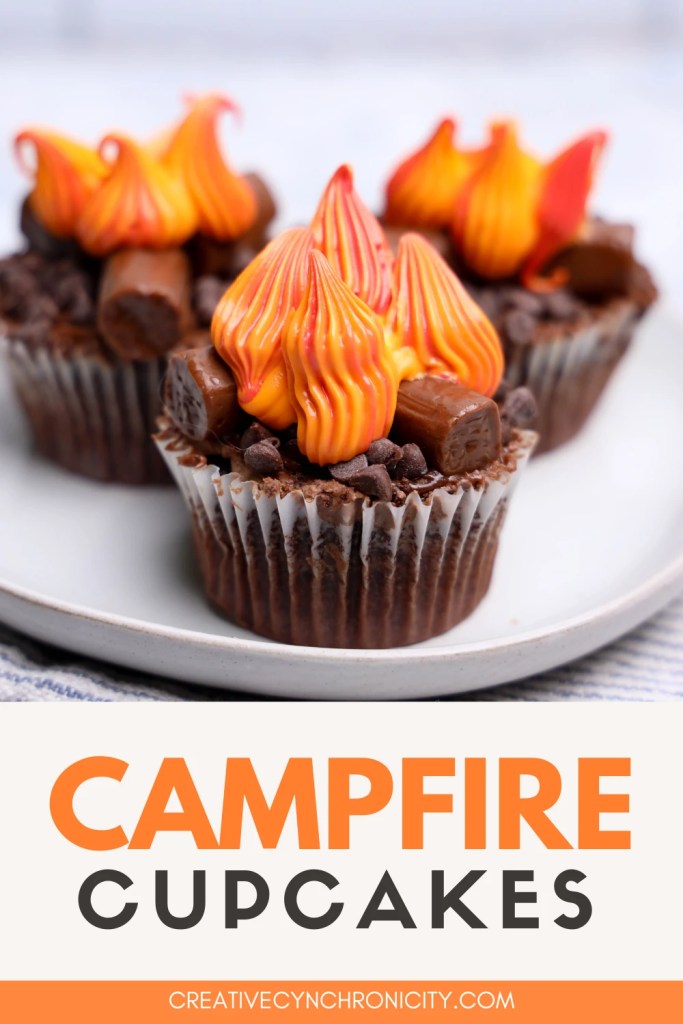 Campfire cupcakes decorated with Tootsie Roll logs, chocolate chip coals, and colorful frosting flames.