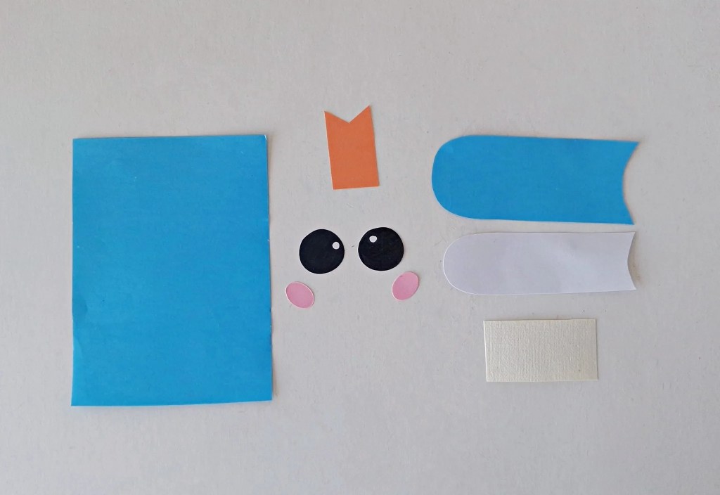 Colored paper pieces cut out for making a notebook paper bag puppet.