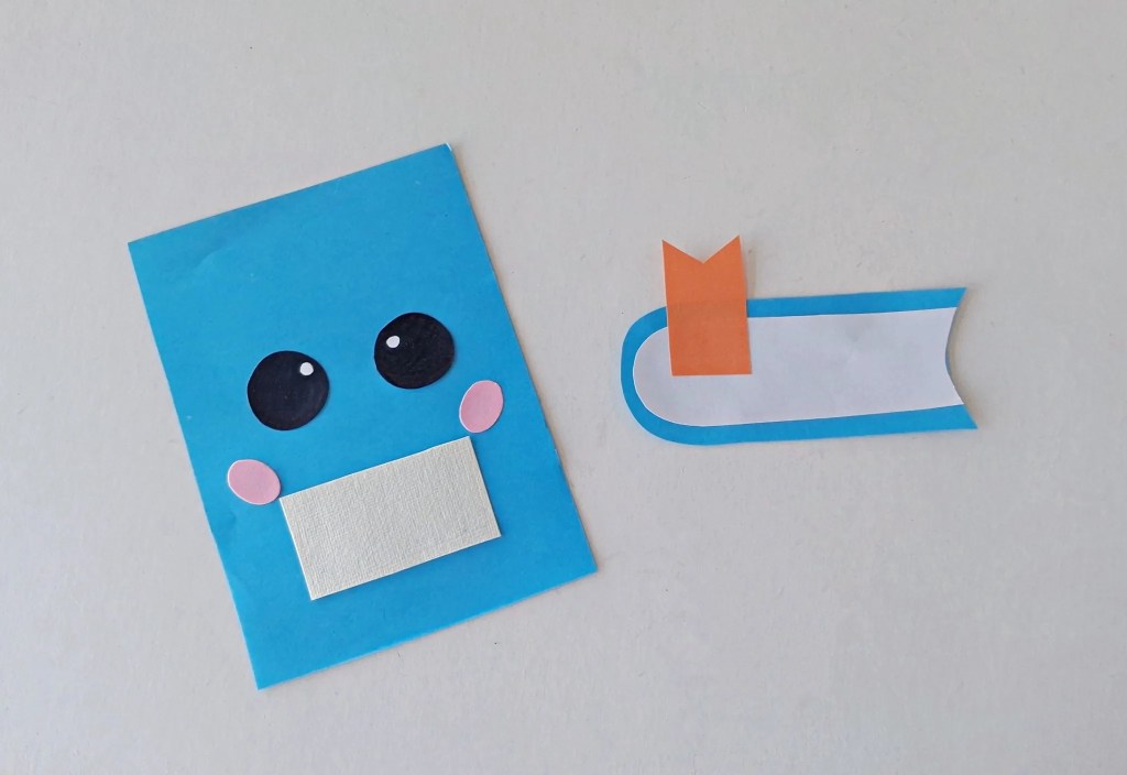 Face, label, page, and orange bookmark added to the blue notebook craft.