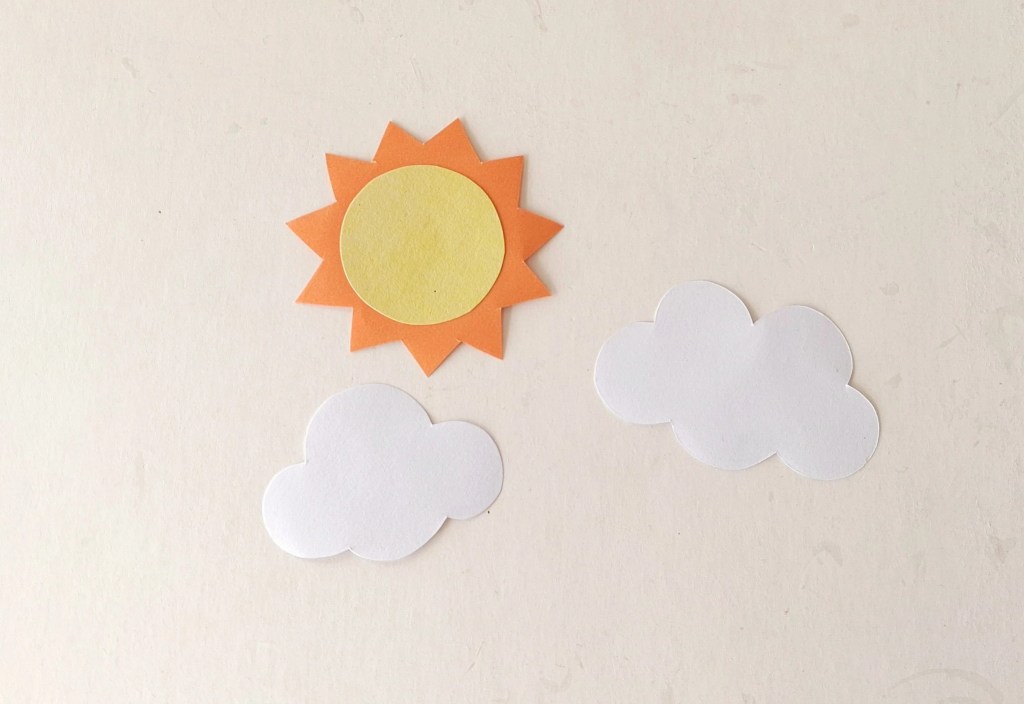 Paper sun and fluffy clouds for decorating the paper plate school bus craft.