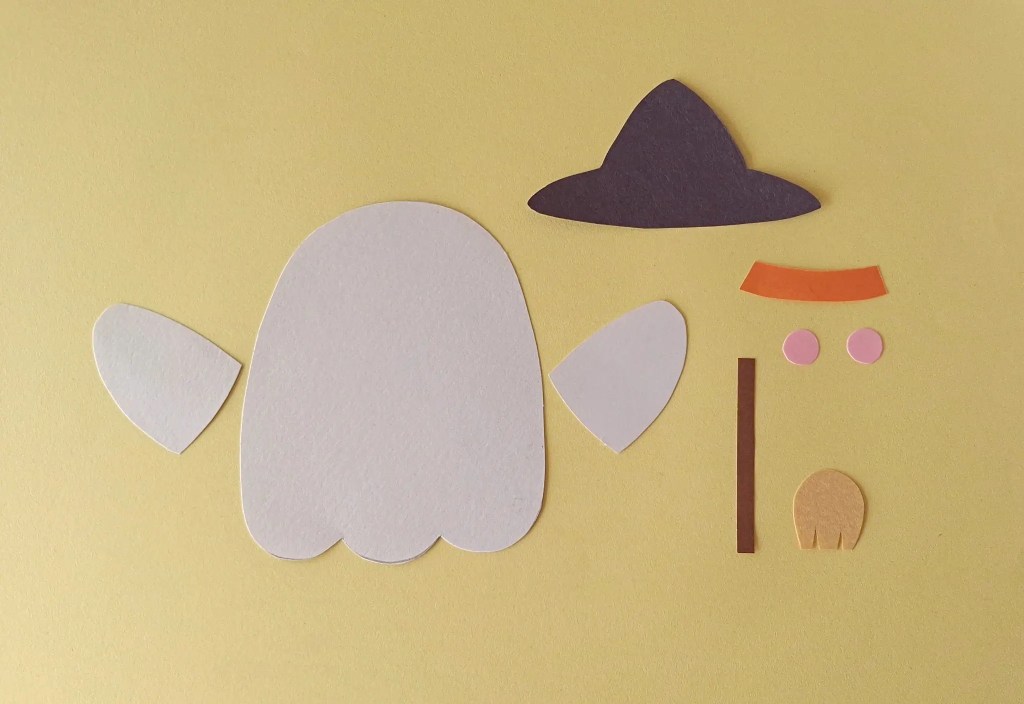 Paper pieces cut out to make a moving ghost puppet with a witch hat and broom