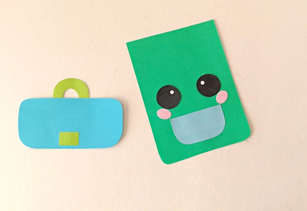 Eyes and pink cheeks attached above the pocket on the green backpack puppet.