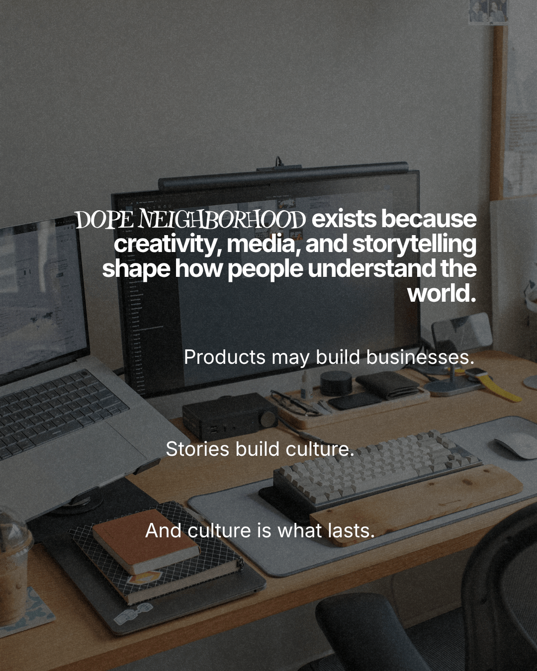 A workspace featuring a computer setup with a laptop and external monitor, surrounded by notebooks, a keyboard, and stationery, with text overlay discussing creativity, media, and storytelling.
