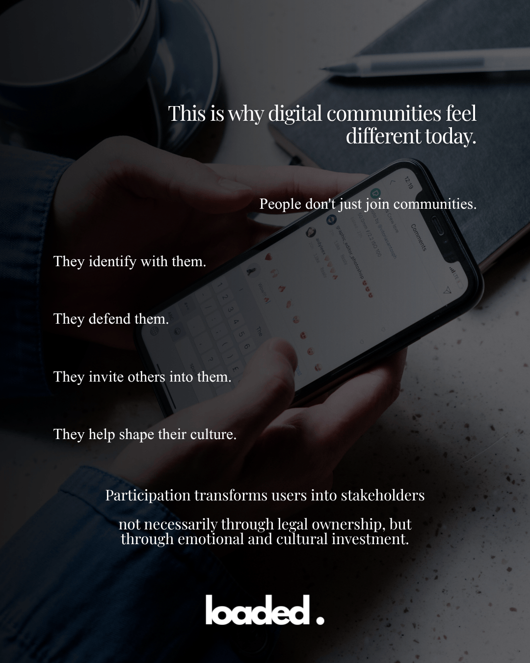 A close-up of a hand holding a smartphone displaying text about digital communities, with a blurred background of a coffee cup and a pen on a table.