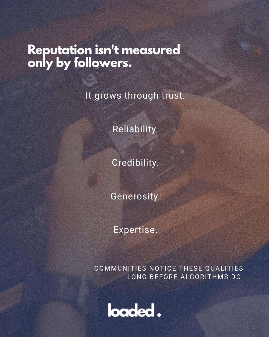 An individual holding a smartphone displaying text about reputation, trust, and community values, with a blurred background of a keyboard.