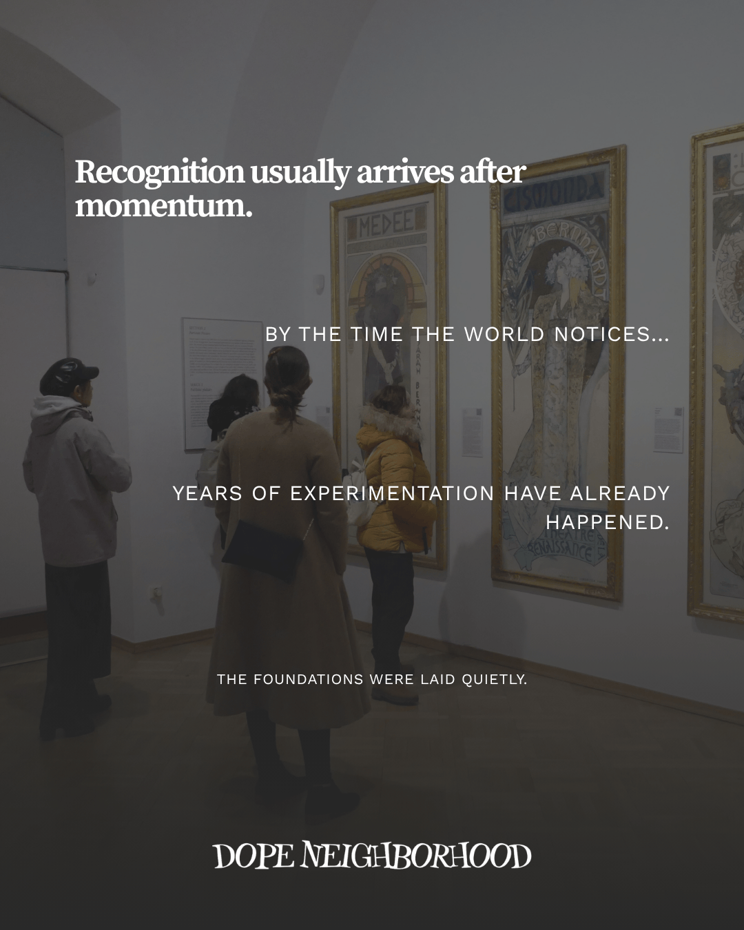 Visitors observing framed artwork in an art gallery, with informative plaques displayed nearby.