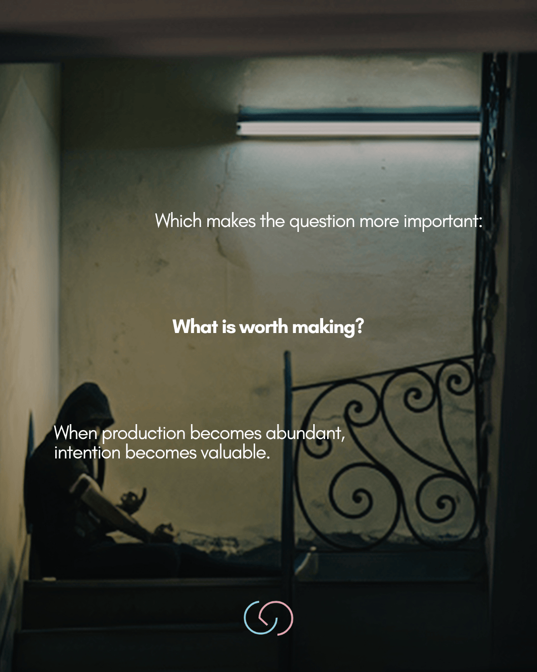 A person sitting on stairs in a dimly lit space, with a neon light overhead. Text overlay asks, 'What is worth making?' and states, 'When production becomes abundant, intention becomes valuable.'