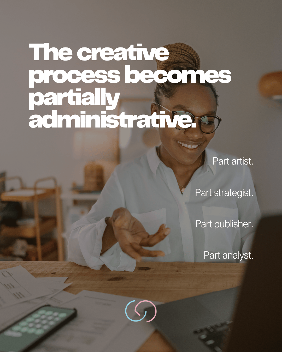 A smiling woman with glasses engaging in a video call, surrounded by paperwork and a laptop, conveying the message about the administrative side of the creative process.