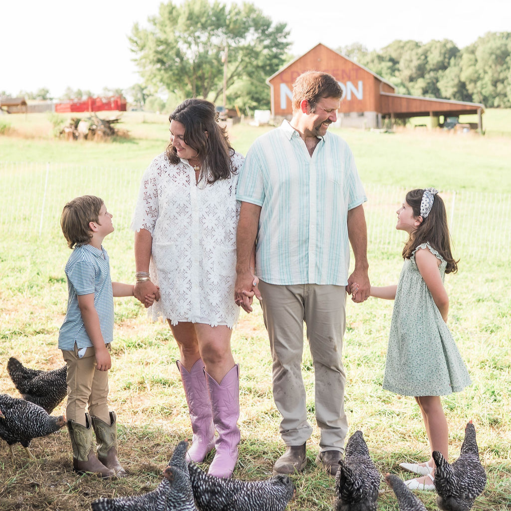 Family on regenerative farm with pasture-raised chickens roaming.