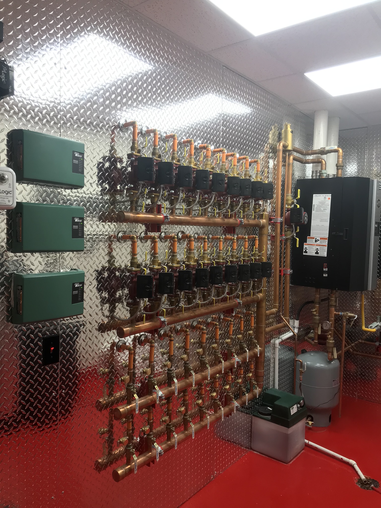 Boiler room showing red floor and silver diamond plate backing. Clean and organized rows of piping and meters