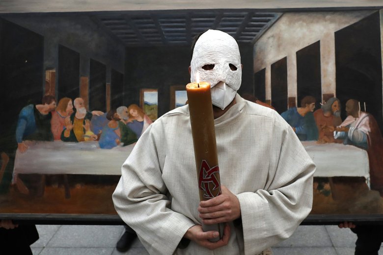 A participant wearing a mask holds a candle as he stands in front of a depiction of the painting the Last Supper during an Easter procession marching through the streets of Ceske Budejovice, Czech Republic, Thursday, April 1, 2021. (AP Photo/Petr David Josek)