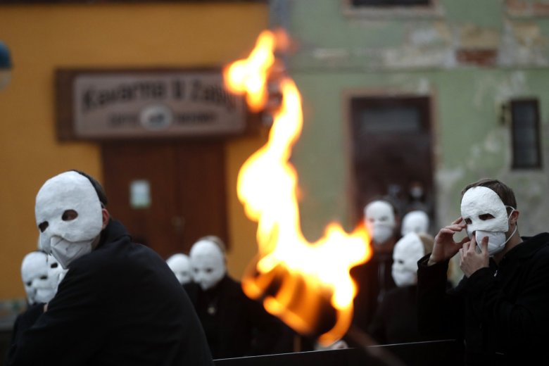 Participants dressed in black, wearing masks, beating drums and pushing small carts making a synchronized and loud sound take part in an Easter procession marching through the streets of Ceske Budejovice, Czech Republic, Thursday, April 1, 2021. (AP Photo/Petr David Josek)