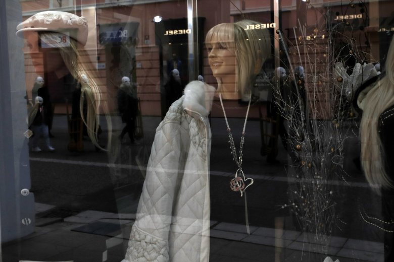 Participants dressed in black, wearing masks, beating drums and pushing small carts making a synchronized and loud sound are reflected in a shop window as they take part in an Easter procession marching through the streets of Ceske Budejovice, Czech Republic, Friday, April 2, 2021. (AP Photo/Petr David Josek)