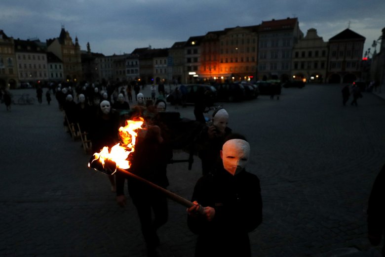 Participants dressed in black, wearing masks, beating drums and pushing small carts making a synchronized and loud sound take part in an Easter procession marching through the streets of Ceske Budejovice, Czech Republic, Thursday, April 1, 2021. (AP Photo/Petr David Josek)