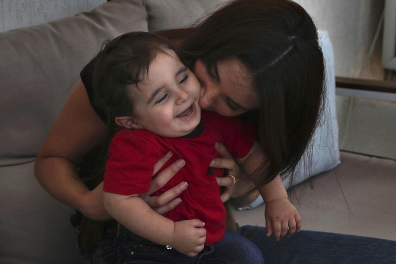 Emmanuelle Khnaisser, kisses her son, one-year-old Georges Khnaisser, at her house in the town of Jal el-Dib, north of Beirut, Lebanon, Tuesday, July 10, 2021. Khnaisser was about to give birth to her first son and was in the last stages of labor when the massive blast tore through the hospital, smashing windows, doors and machines in the operations room and riddling her lower body with tiny pieces of flying glass. (AP Photo/Bilal Hussein)