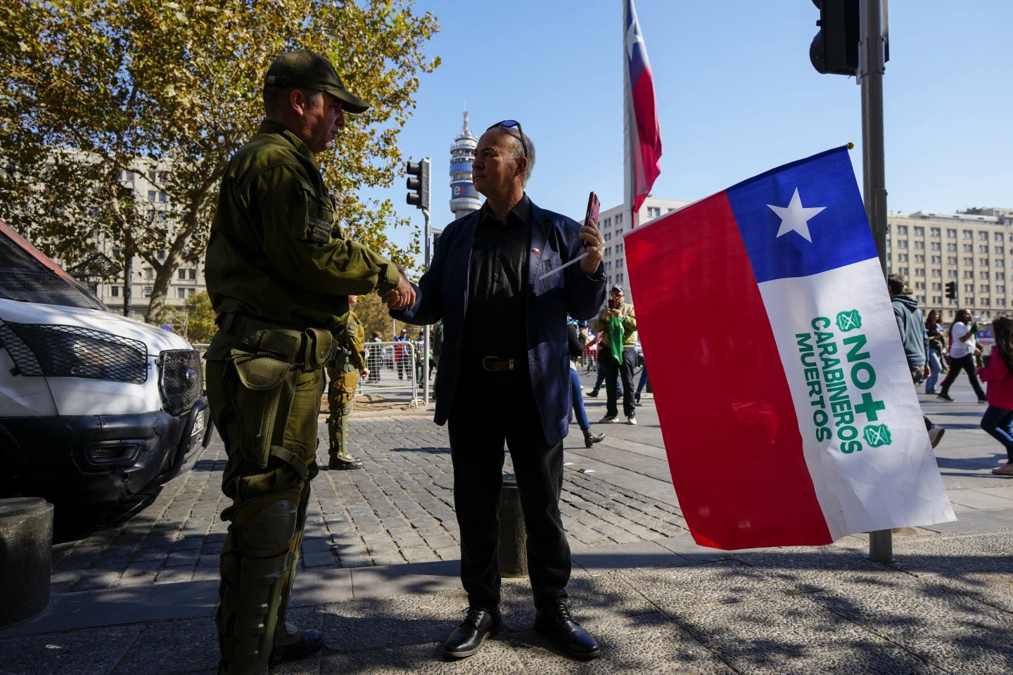 A man offers his condolences to a Chilean police officer after the brutal slayings of three officers on April 27, 2024. (Credit: Esteban Felix/AP.)