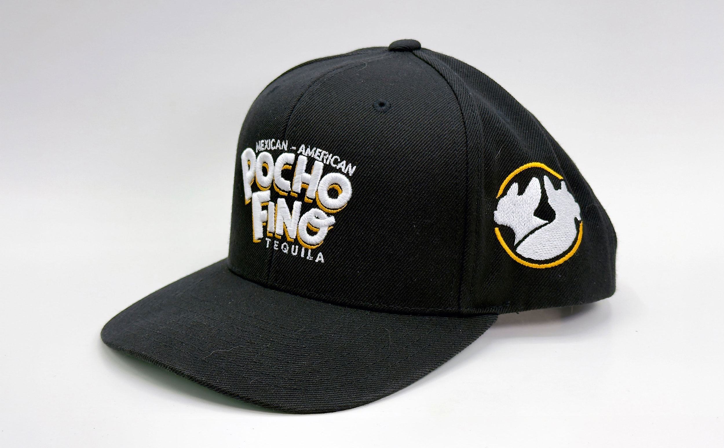 Black baseball cap with embroidered Mexican-American Tequila branding and a yellow-outlined mountain patch on the side image center-right area.