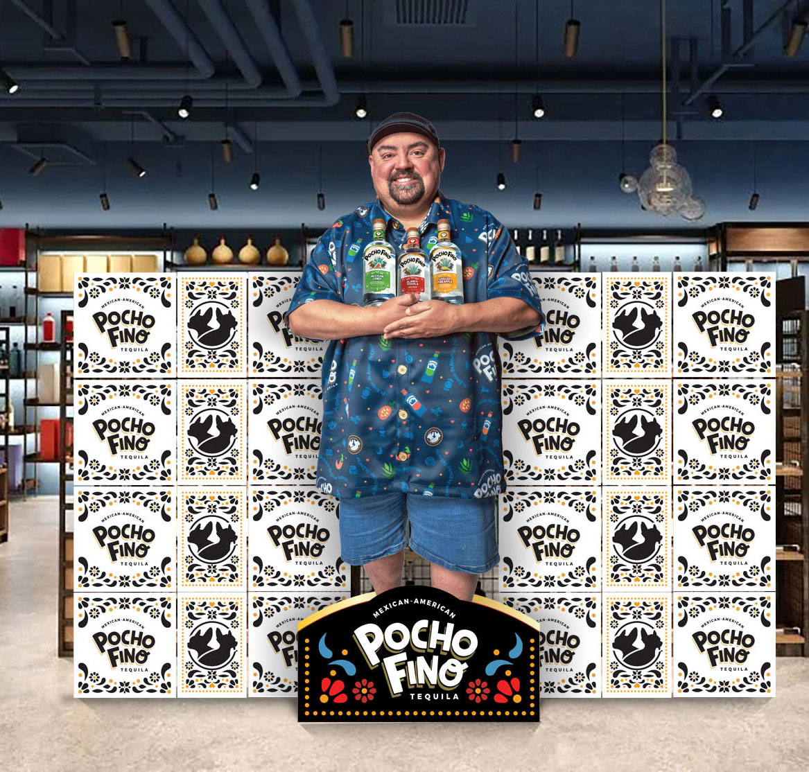Smiling man in a blue printed shirt with a cap stands in front of stacked Pocho Fino tequila boxes, holding bottles.