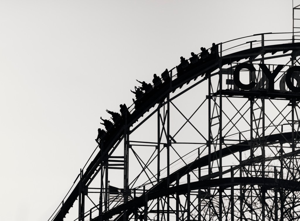 Silhouette of a car on a roller coaster about to go down a large hill