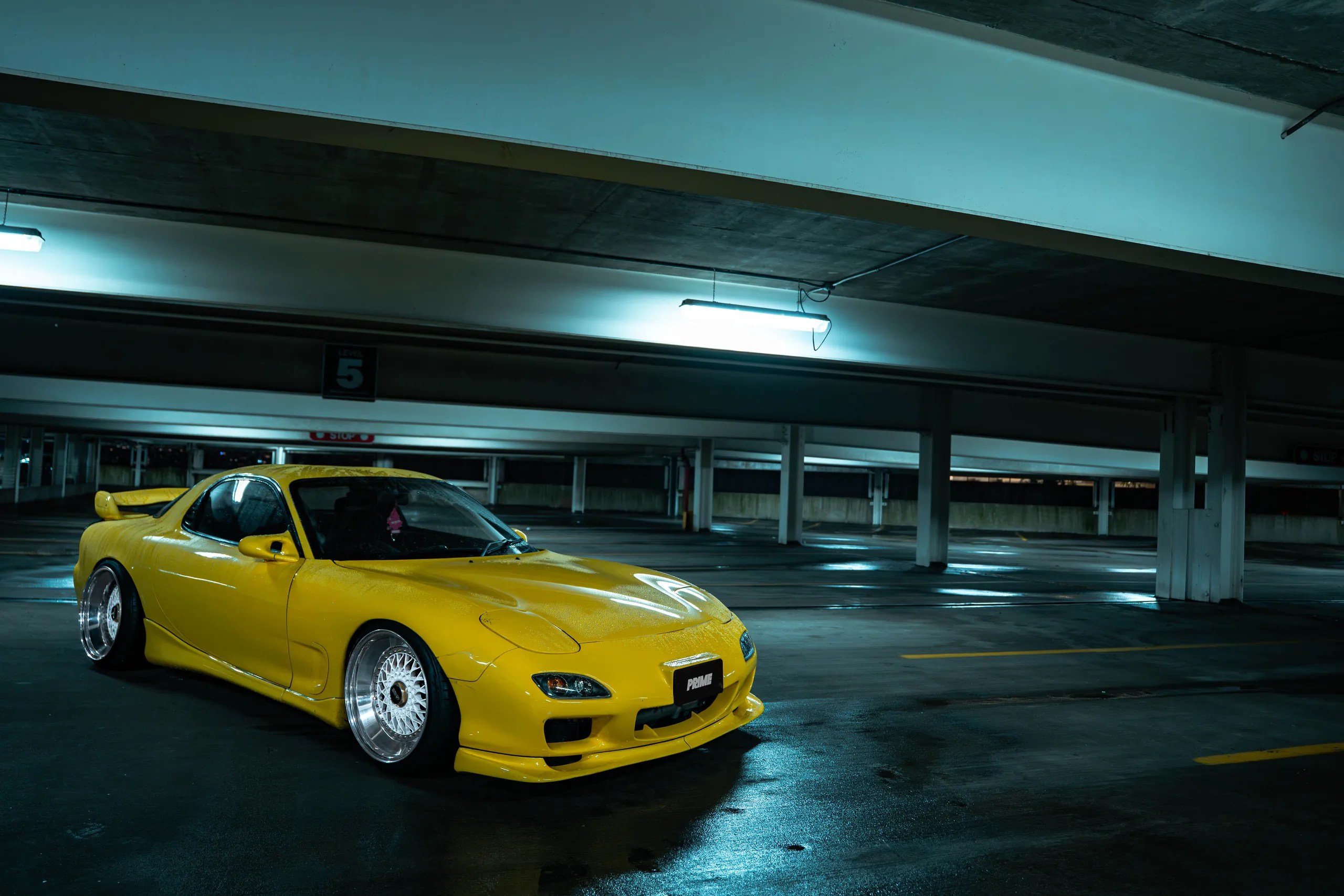Taxi-yellow widebody Mazda RX7 FD in a dimly lit Jersey City parking garage