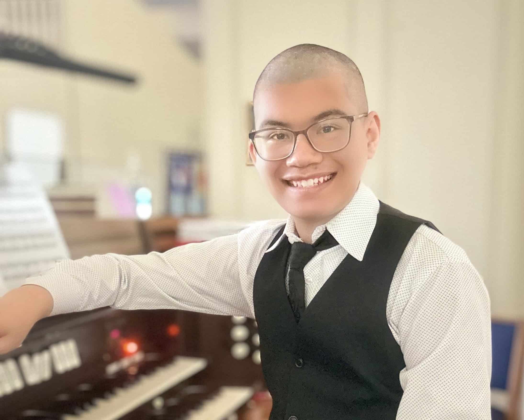 Young man smiling at piano during church service at Christ the King Episcopal Church.