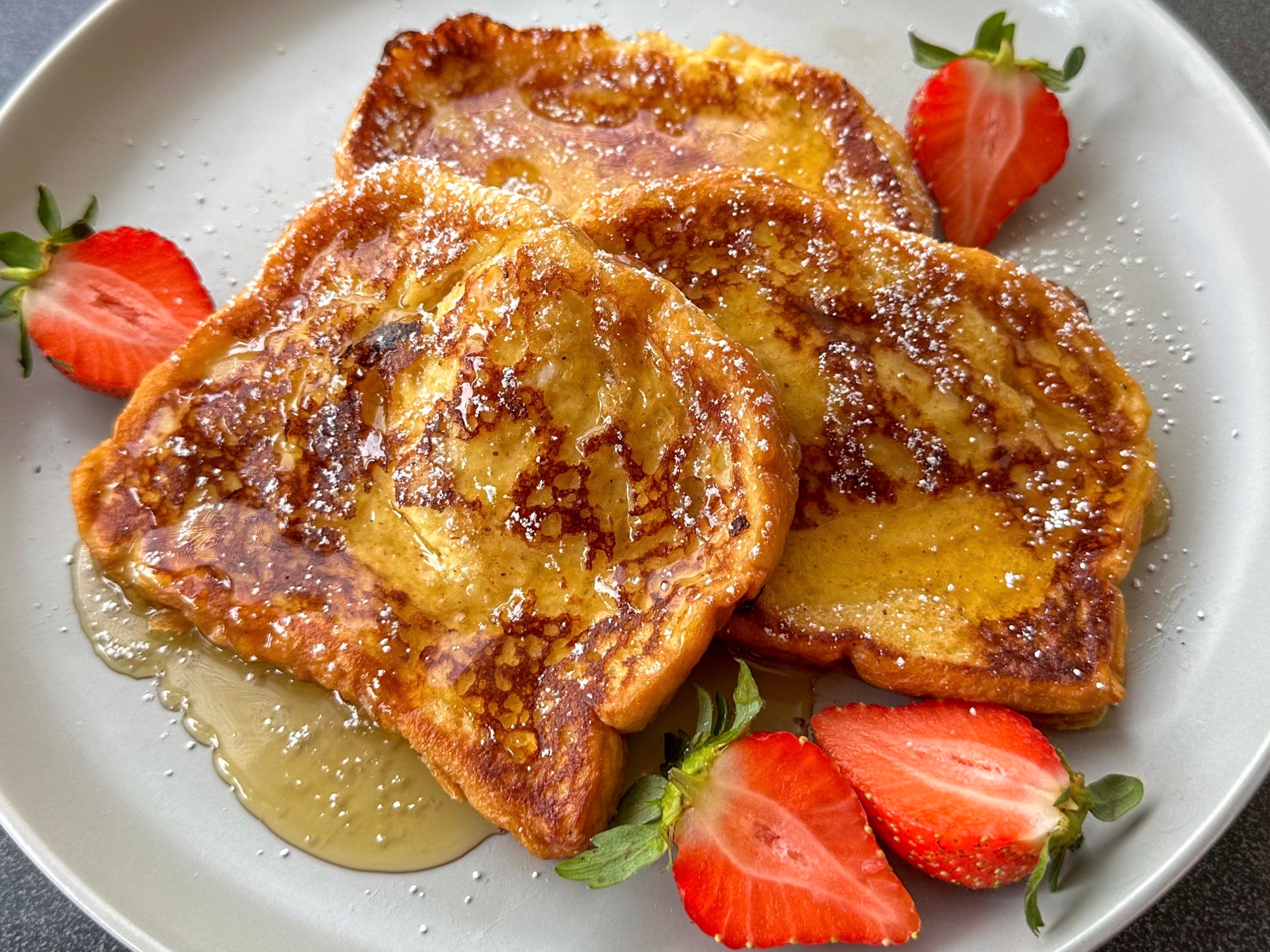 French toast topped with syrup and served with strawberries