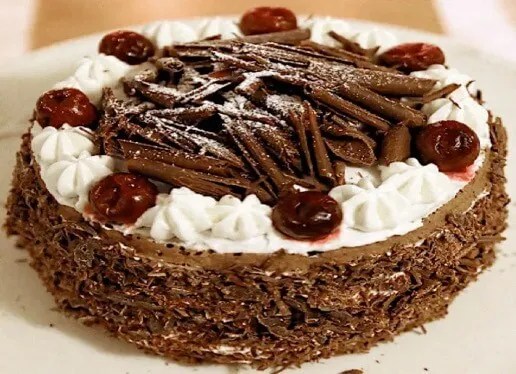 Forêt noire recouverte de chantilly, de copeaux de chocolat et de griottes, une part coupée